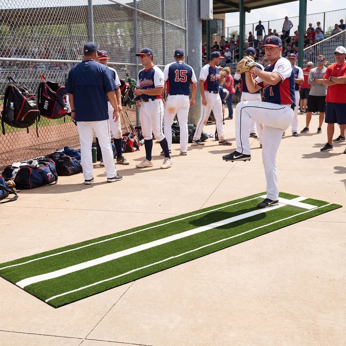 A baseball pitcher practices on a green artificial turf training aid at a baseball field