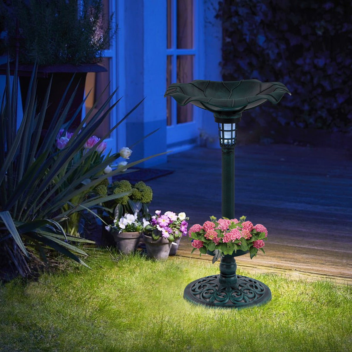 The bird bath and feeder set at dusk, with a soft light illuminating the garden