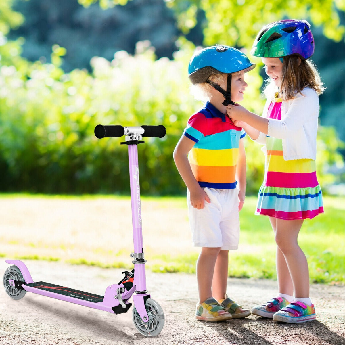 Two children in helmets with the purple scooter in a park setting