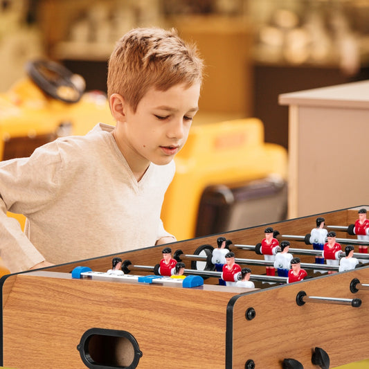 A young boy playing with the table football game