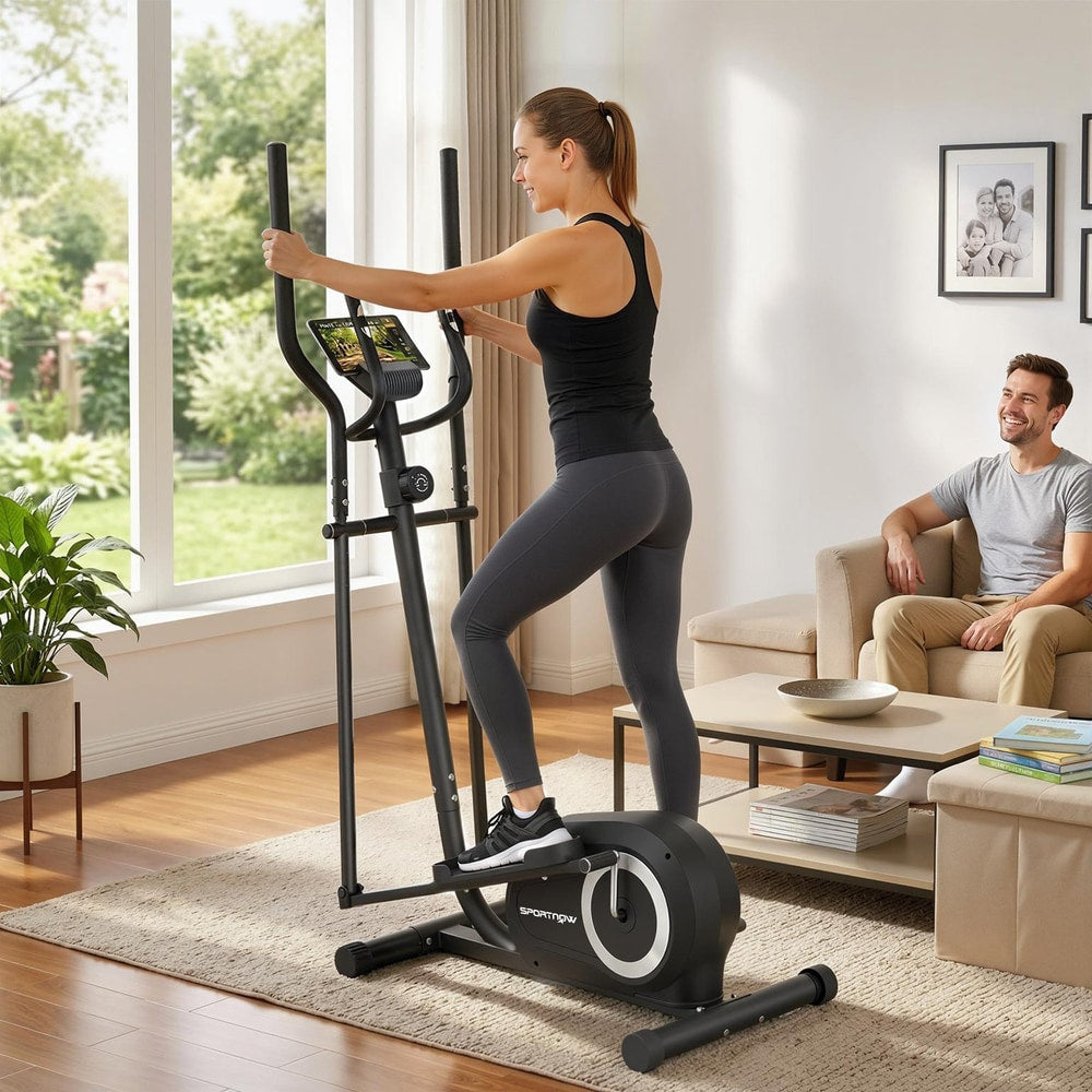 Woman using the elliptical cross trainer in a living room with a man watching