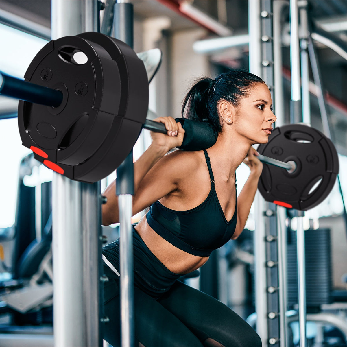 A woman is using the weight plates set for squats in a gym
