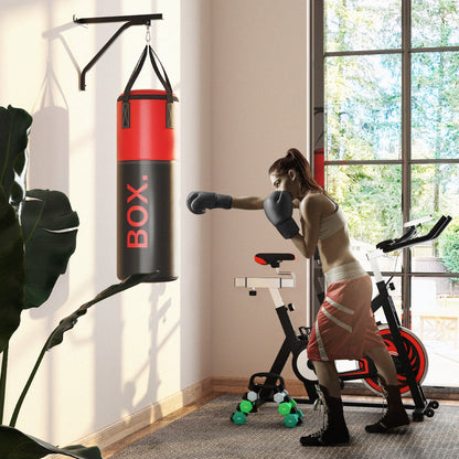 Woman in boxing gloves punching the red and black boxing bag in a room with a bike