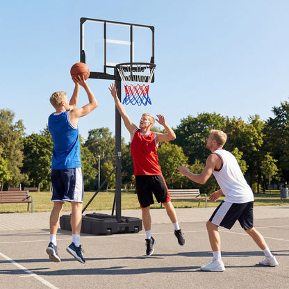 The basketball hoop standing on an outdoor court with three men playing a match