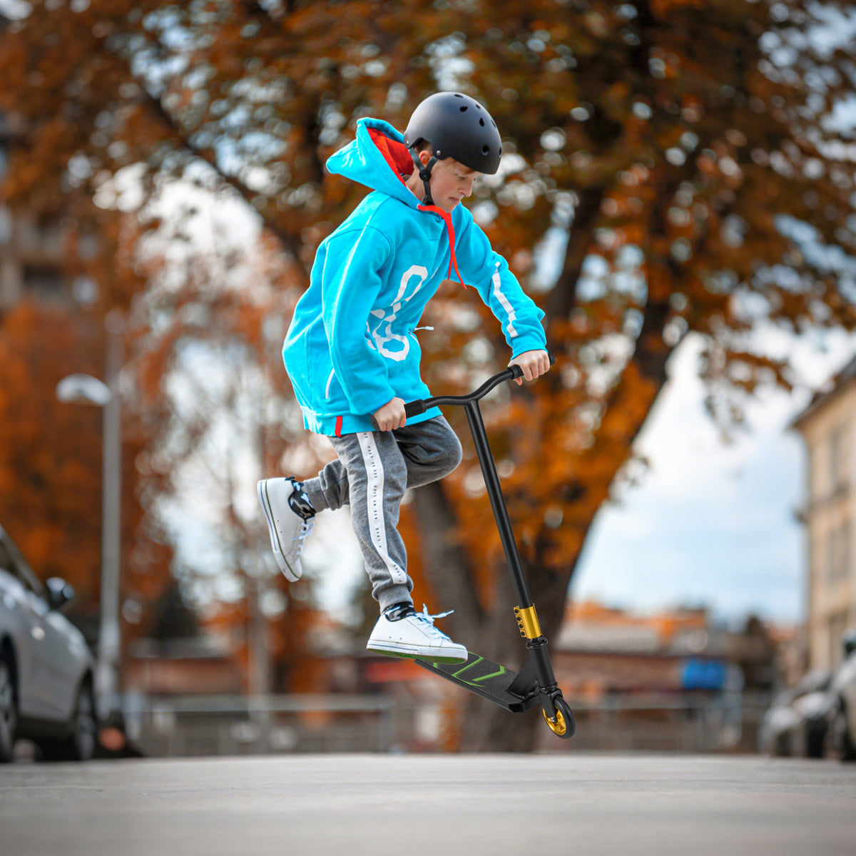 A child in a blue hoodie performing a jump on the stunt scooter
