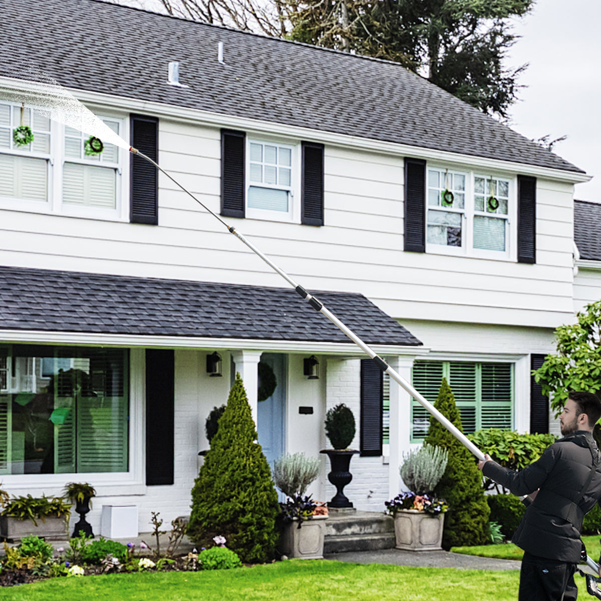 The garden tool being used to spray water onto the upper windows of a large house