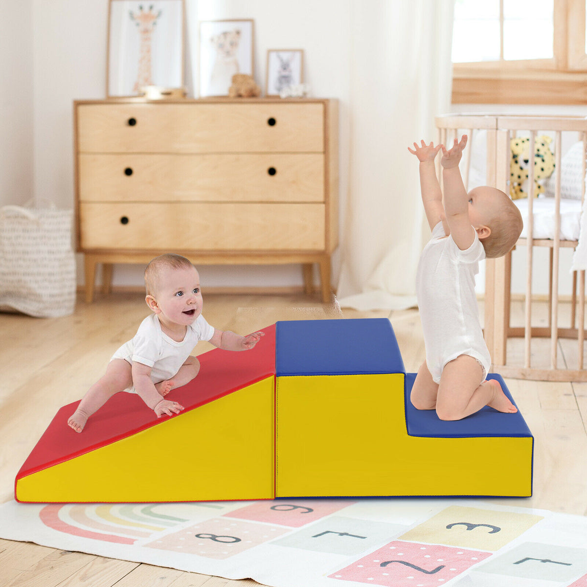 The soft play set in a nursery with a baby climbing the steps and another reaching upwards