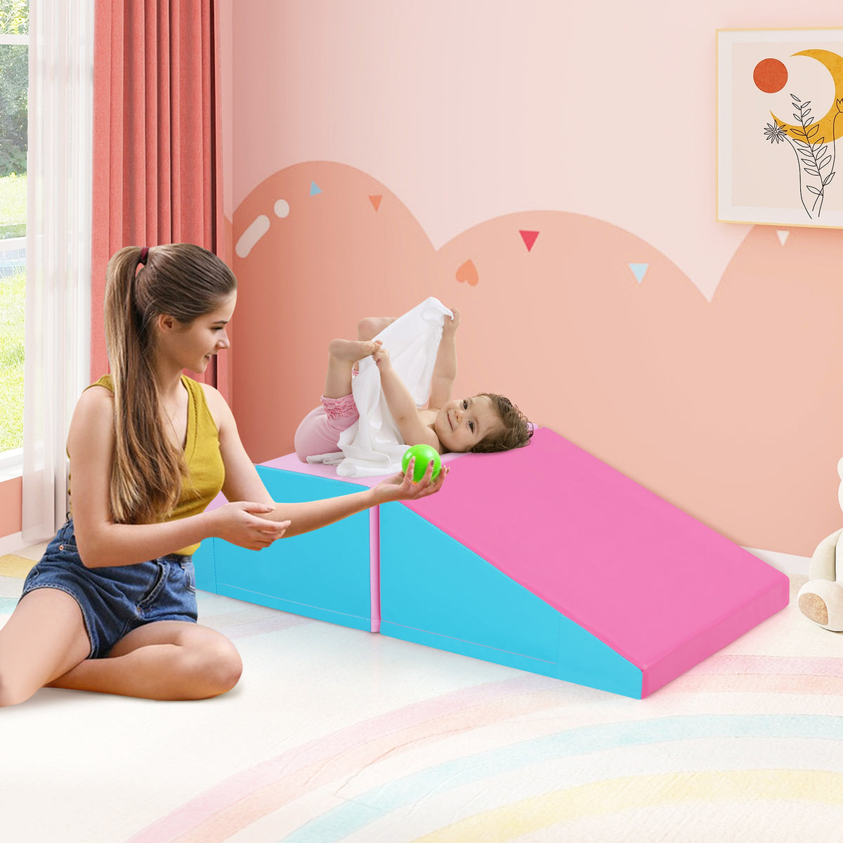 The soft play set in a nursery room with a mother playing with her baby on the pink and blue ramp