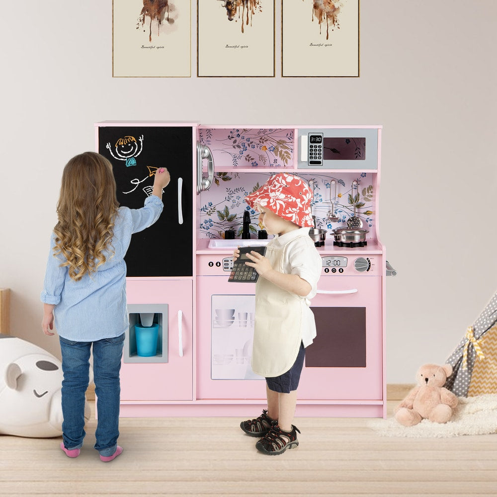 Two children playing with the cream pink play kitchen set in a room