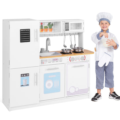A boy in a chef's outfit stands next to the white play kitchen set, holding a pot