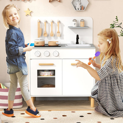 Two young children playing with the white pretend play kitchen