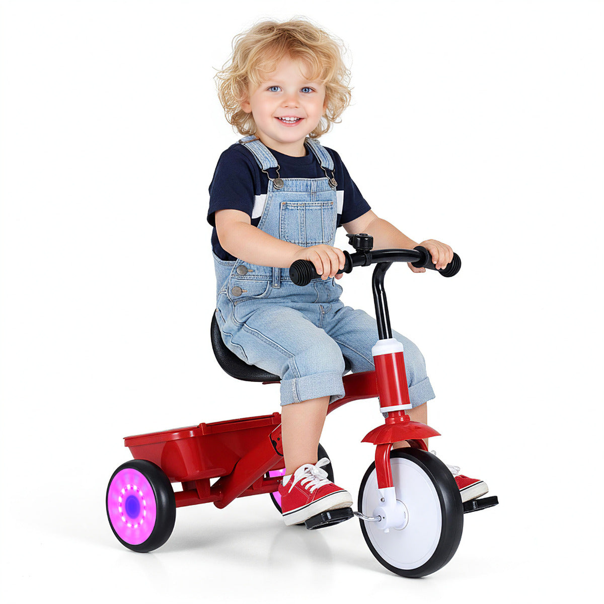 Toddler Tricycle Bike, the ride on toy being ridden by a smiling young boy wearing denim overalls indoors