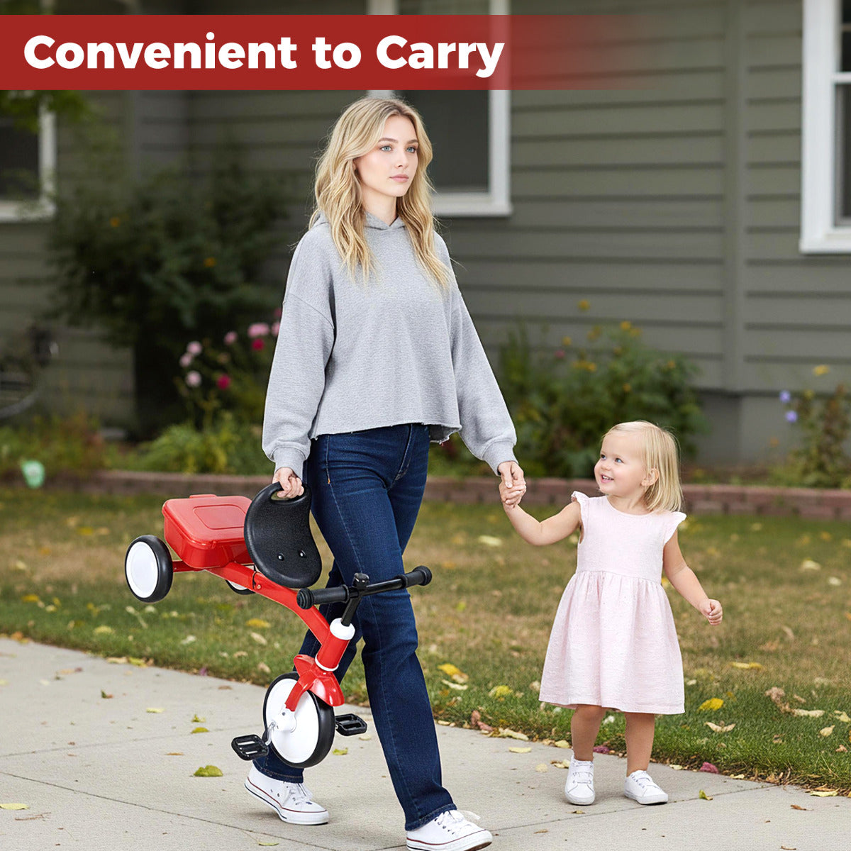 Toddler Tricycle Bike, the ride on toy being carried by a woman walking down a pavement with a young girl