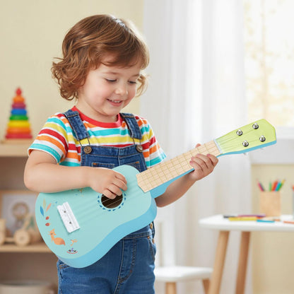 A smiling young boy holding and playing a light blue toy ukulele with a natural wood neck
