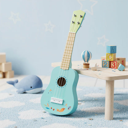 A light blue toy ukulele with a natural wood neck sitting on a wooden table next to children's toys