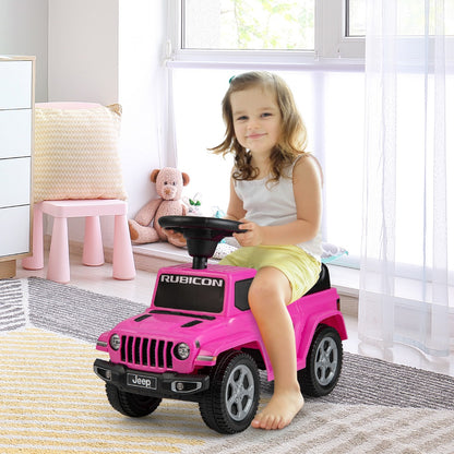 Little girl sitting on the pink ride on push car in a nursery room