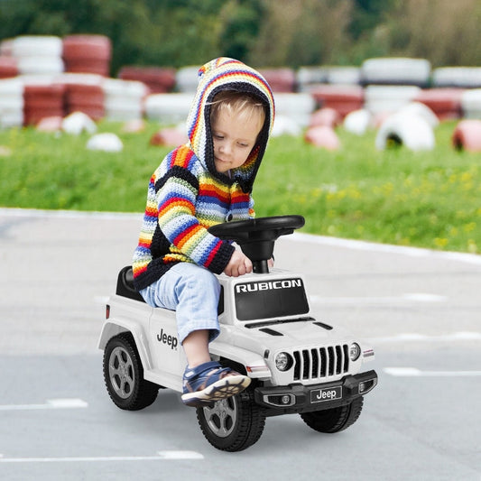 A toddler wearing a colourful hooded jumper sits on the white ride on push car