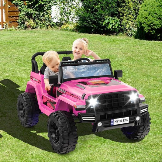 Two young children enjoying a ride in the pink electric car on a sunny lawn