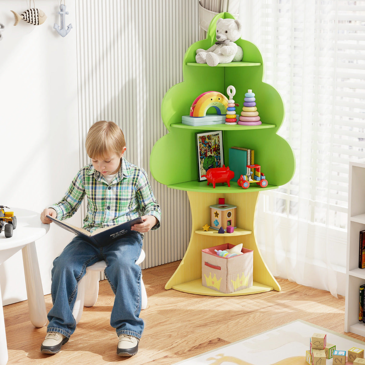 A young boy sitting on a small chair reading a book next to the kids storage unit