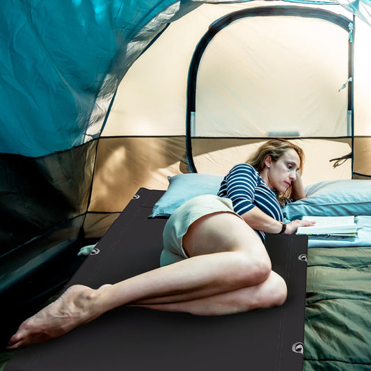 Woman reading on the camping cot inside a tent