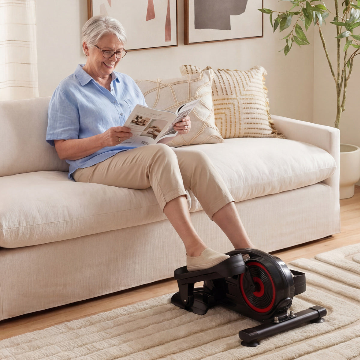 An older woman using the under desk elliptical pedal exerciser while relaxing on a sofa