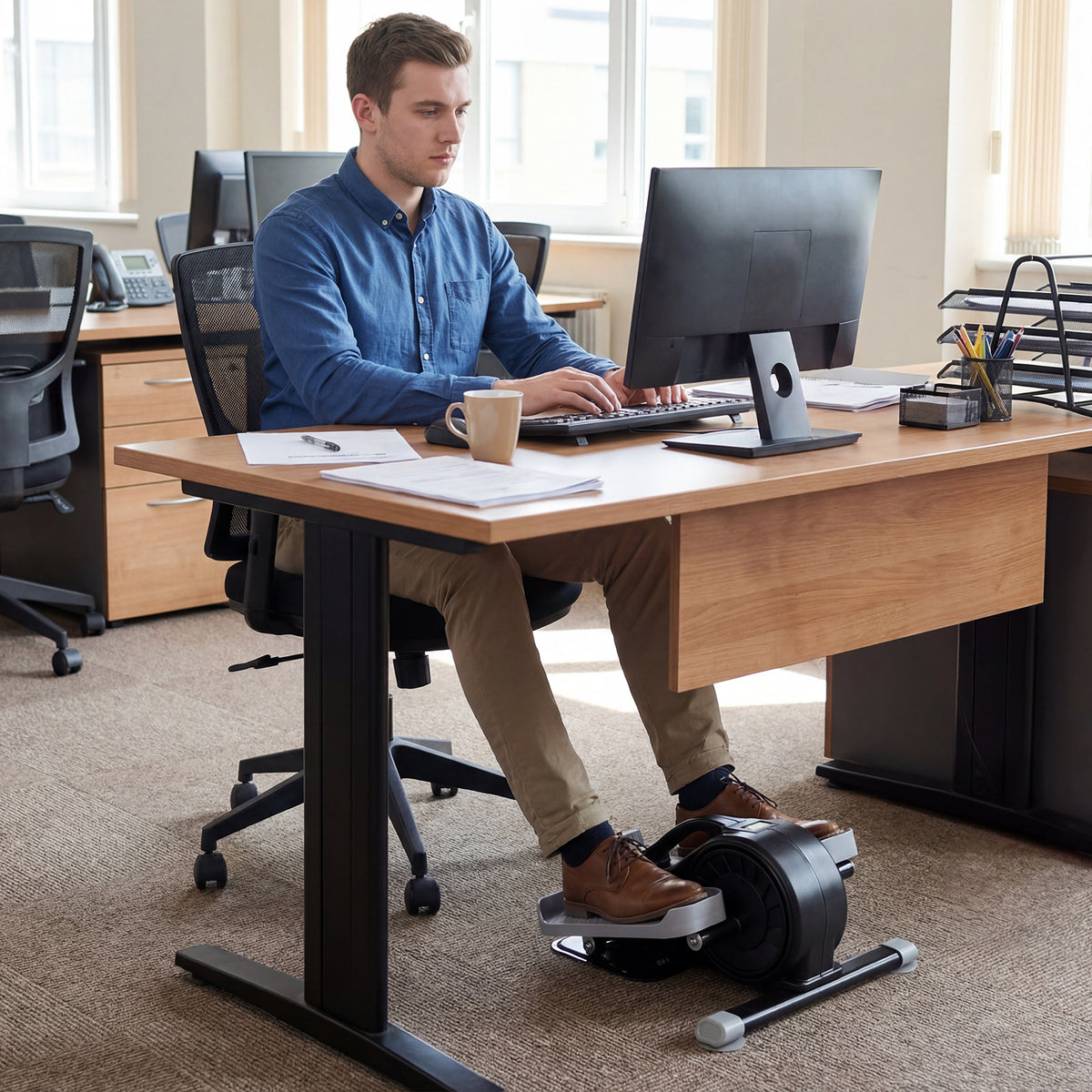 The under desk elliptical pedal exerciser being used by a man working at his desk