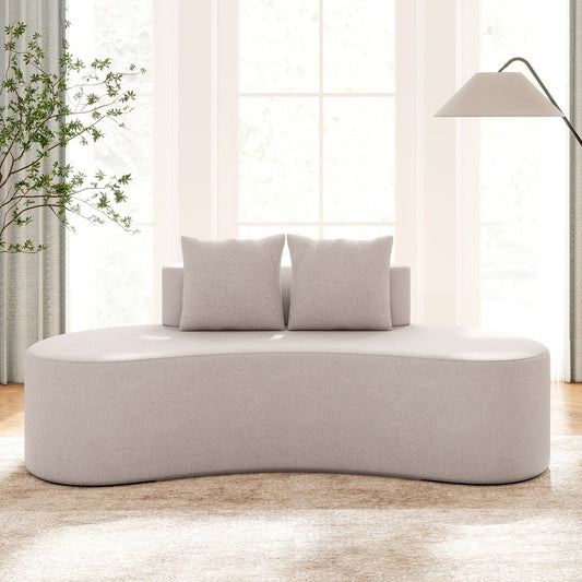 Grey upholstered curved sofa with two pillows in a bright room setting