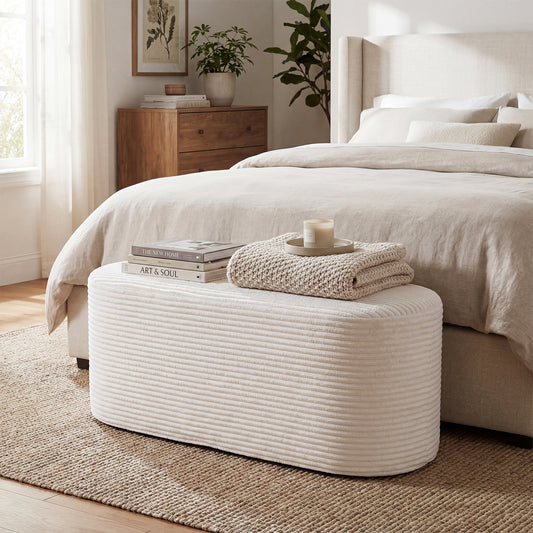 White corduroy upholstered ottoman bench at the end of a bed