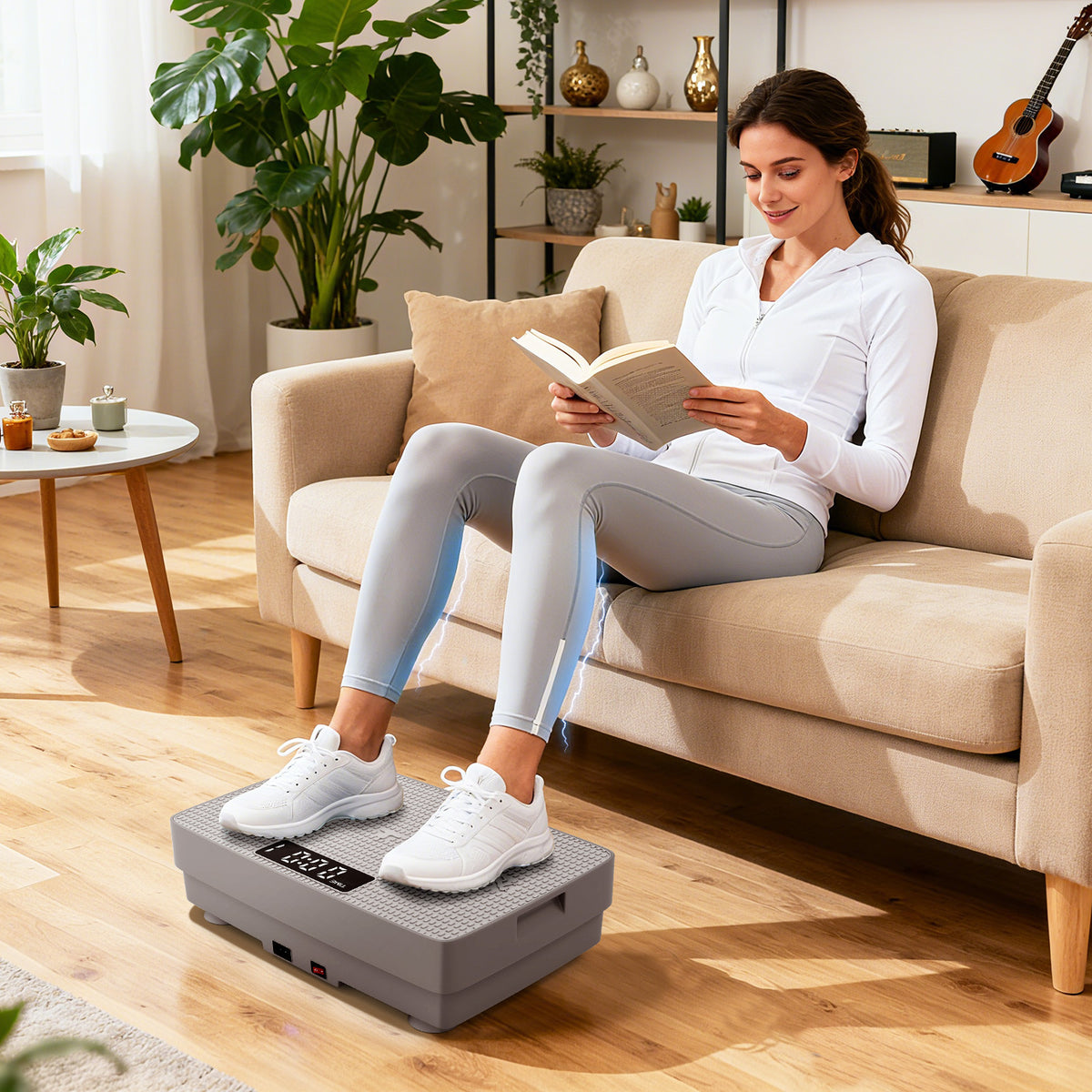 A woman reads a book while sitting on a sofa with her feet on the grey vibration plate exercise machine