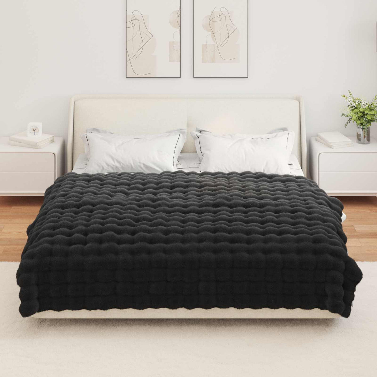 The black faux rabbit fur blanket laid on a bed