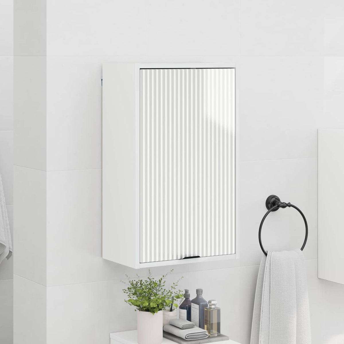 The bathroom vanity unit hanging on a tiled wall next to a towel ring