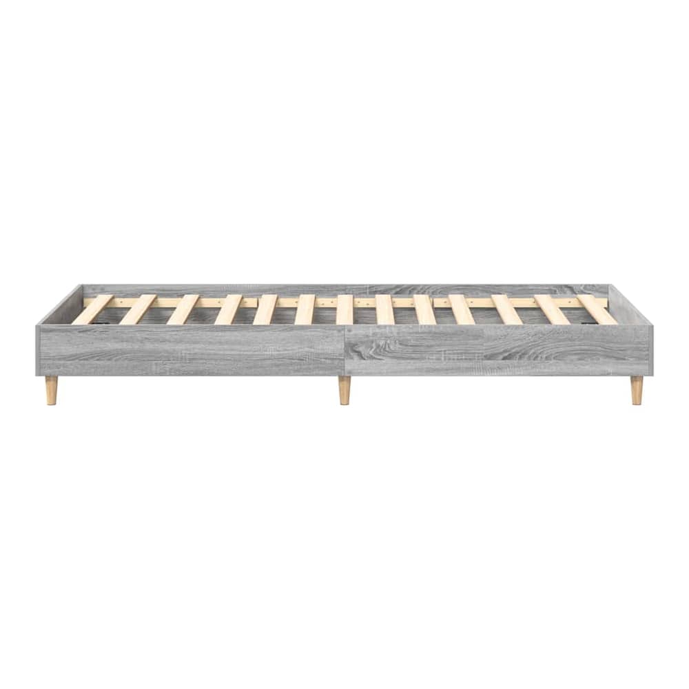 The grey engineered wood bed frame from a low angle, highlighting the legs and base structure