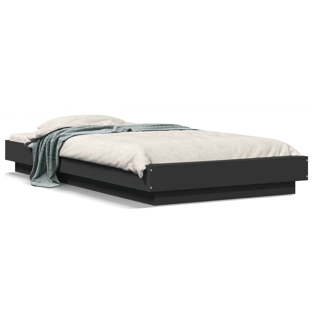 The black small single bed frame with a mattress and throw