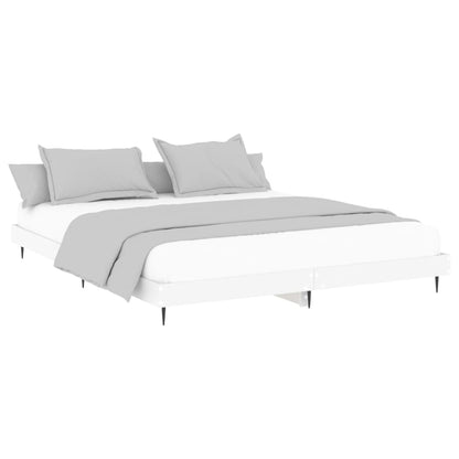 The white bed frame with a mattress and grey bedding viewed from a slightly lower angle
