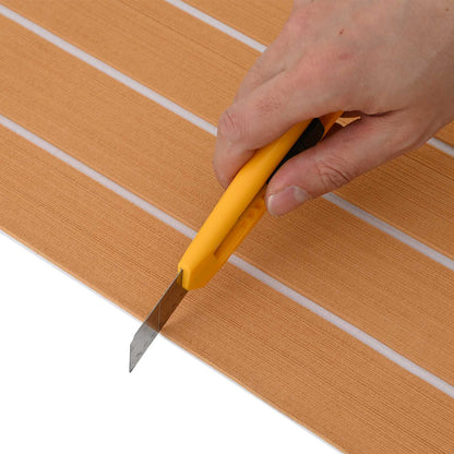 A hand using a utility knife to cut the boat mat to size