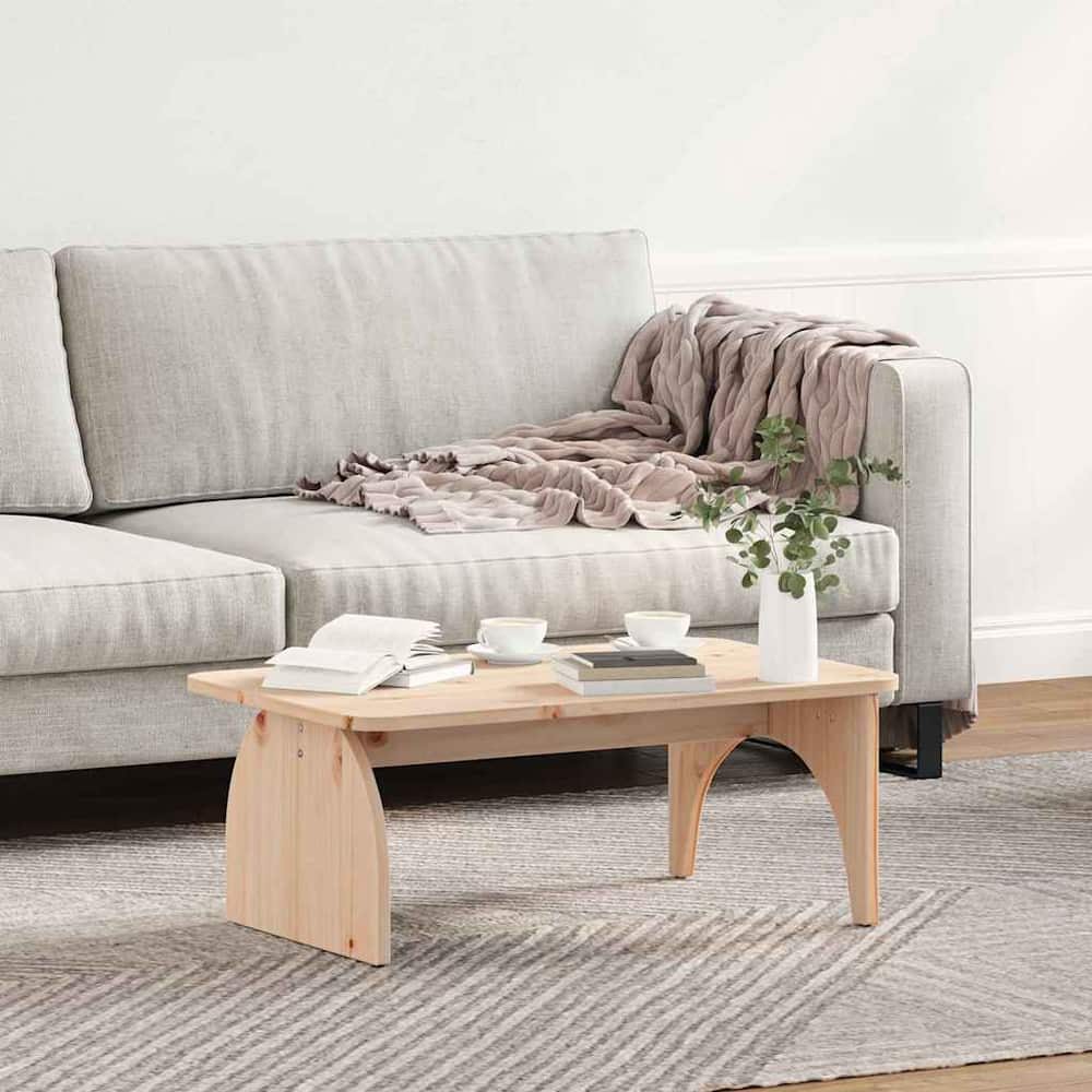 A natural pine wood coffee table placed in front of a sofa on a rug