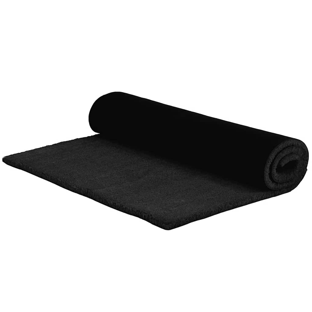 The black tufted coir doormat is partially unrolled on a white background
