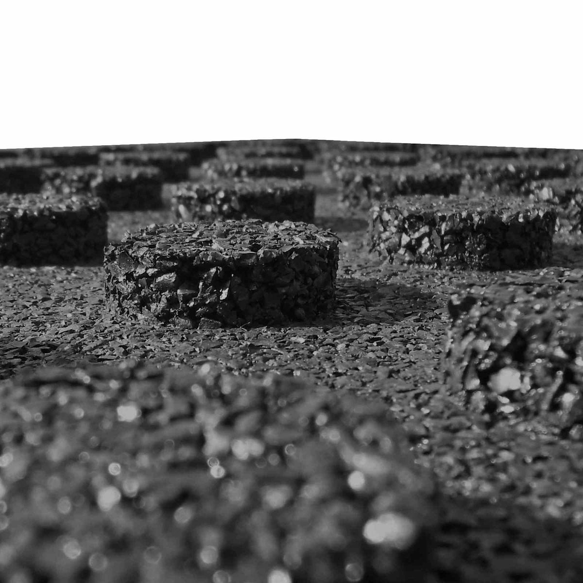 close up of the underside of black rubber fall protection tiles showing the raised circular studs