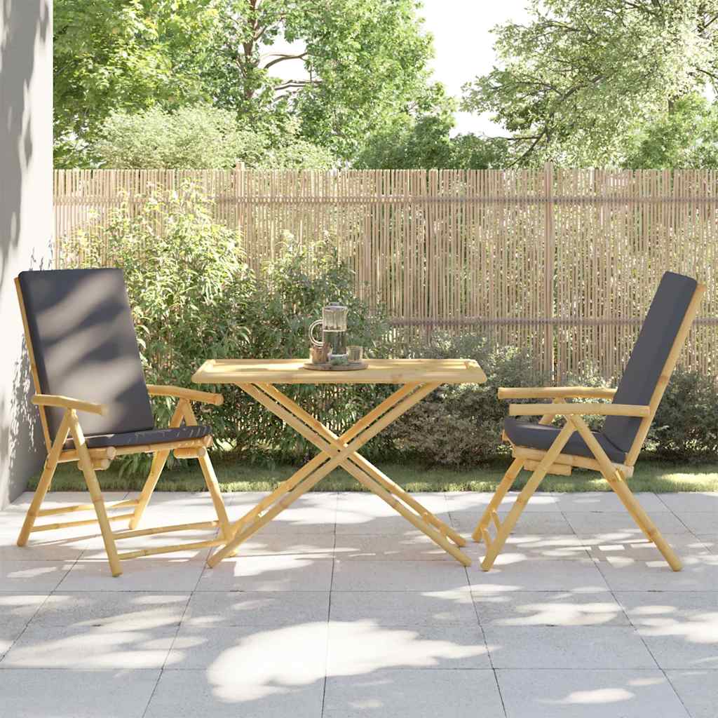 Two chairs and the bamboo garden table arranged on a patio with a bamboo fence behind
