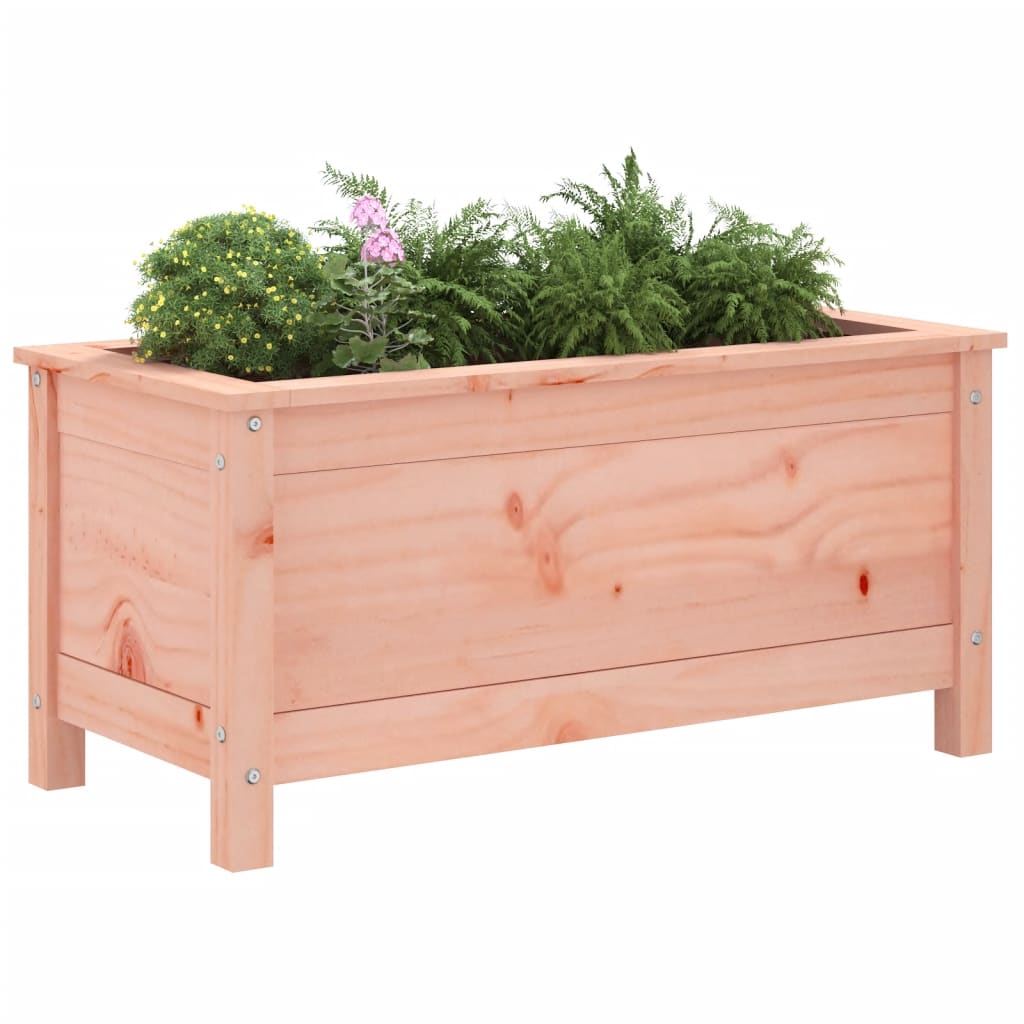The wooden planter filled with green plants and a pink flower