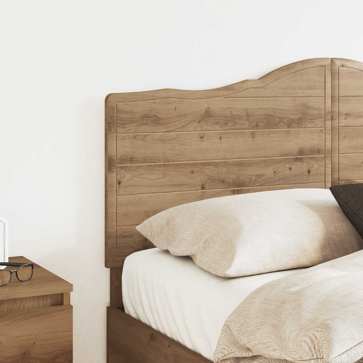 The headboard positioned behind a bed with pillows and bedding in a bright room