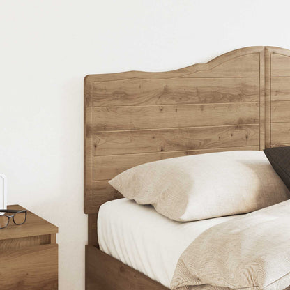 The headboard positioned behind a bed with pillows and bedding in a bright room