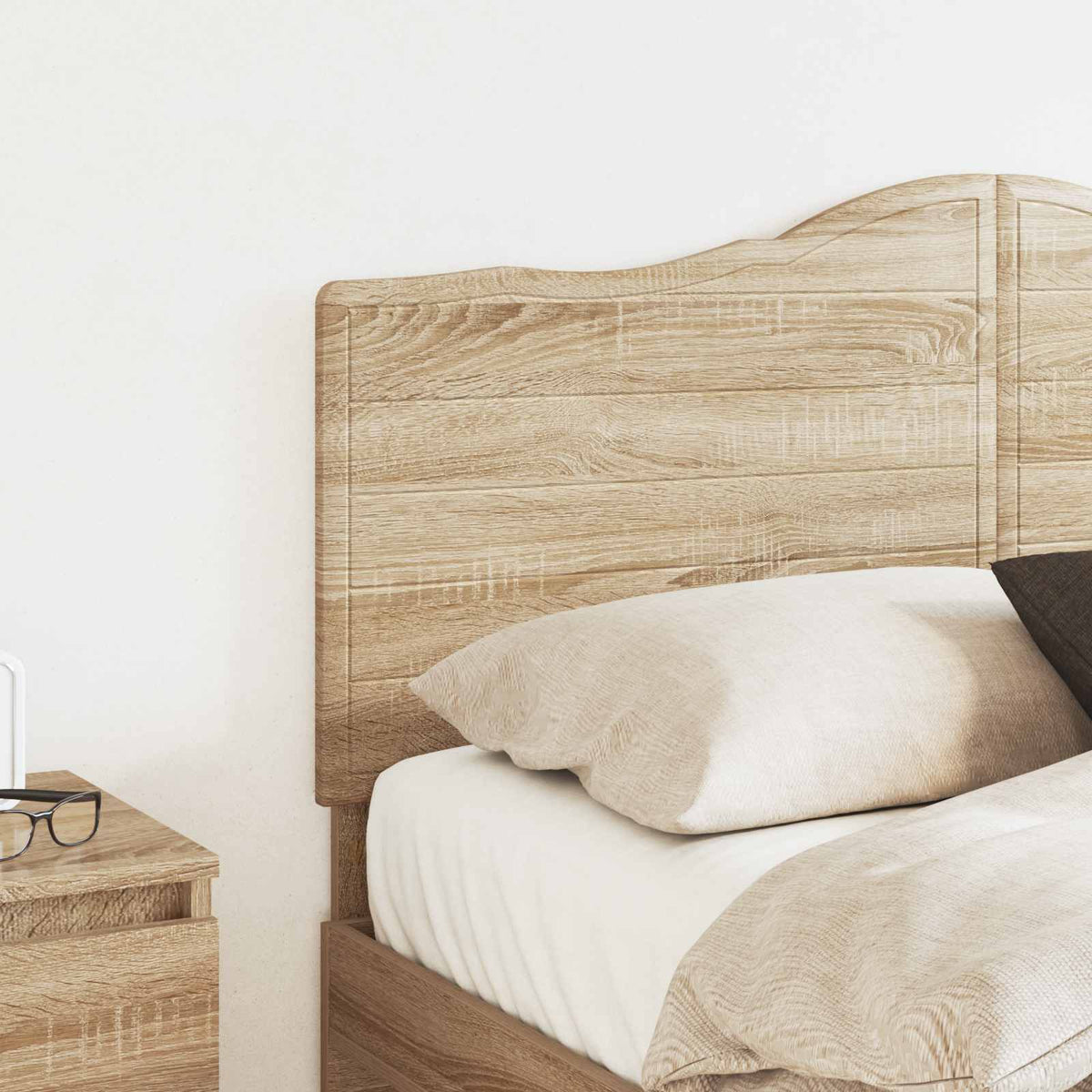 The headboard positioned behind a bed with pillows and a bedside table nearby