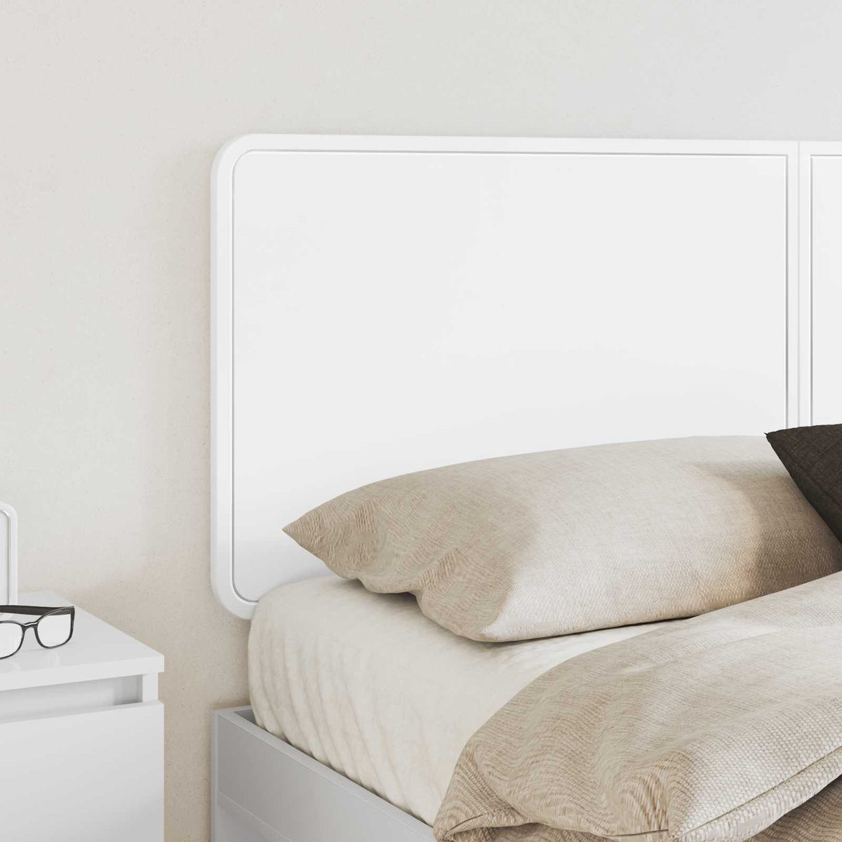 a close-up of the white headboard panel positioned behind a bed with pillows