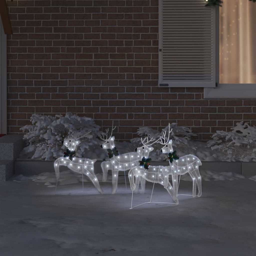 Four illuminated white fabric reindeer figures on a patio at night