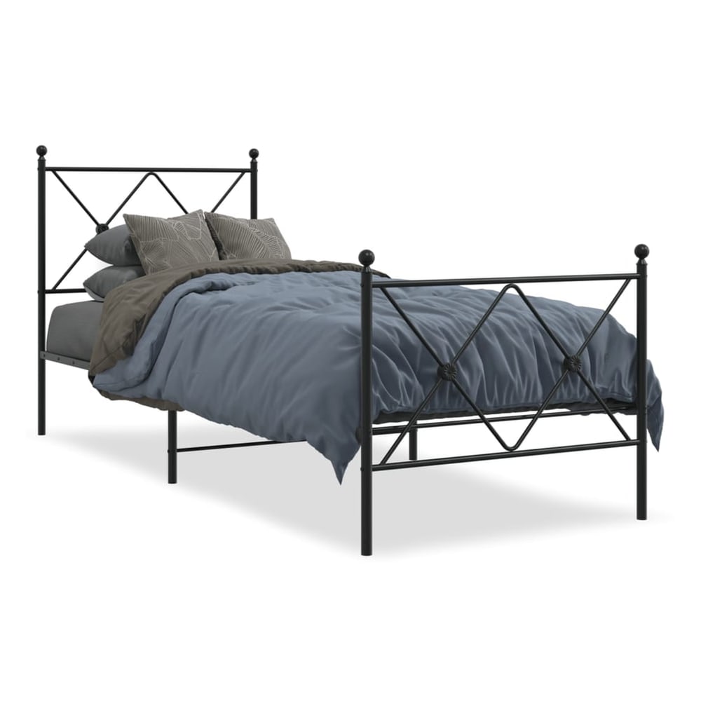 The black metal bed frame with a footboard, made up with a mattress and bedding