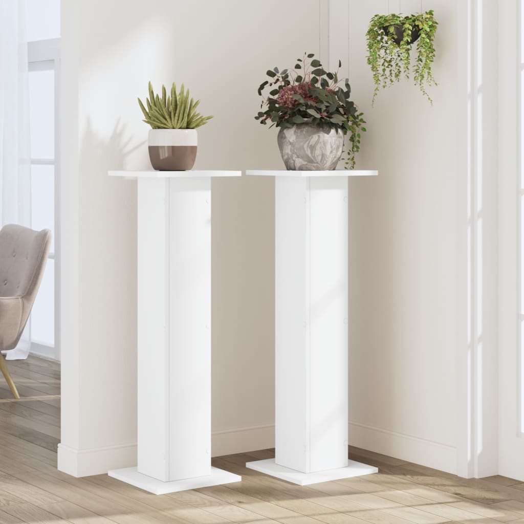 Two white plant stands in a room setting with plants on top