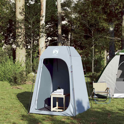 The grey privacy tent with the door open, a chair and table visible inside
