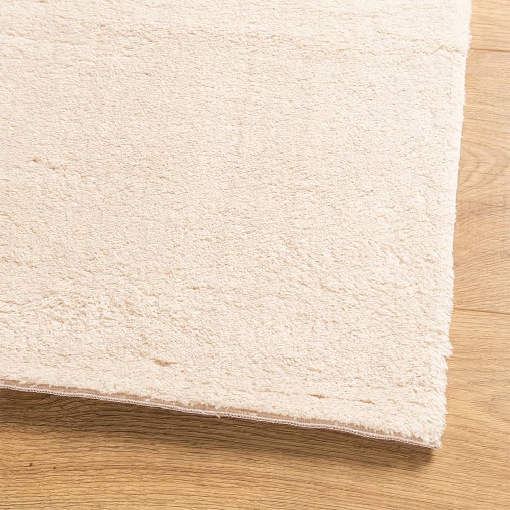 Close up of the soft pile of a beige rug on a wooden floor