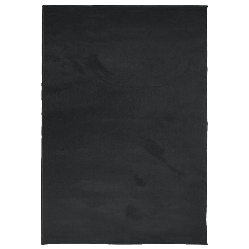 The black short pile rug laid flat on a wooden floor